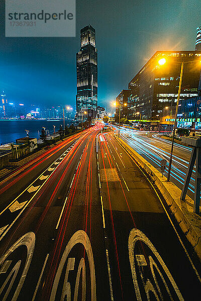 Langzeitbelichtung des fließenden Verkehrs auf der Straße mit modernen Gebäuden im Hintergrund  Hongkong