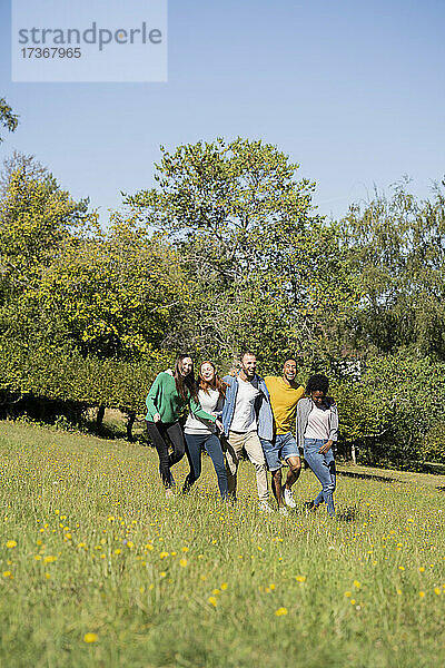 Glückliche junge Freunde haben Spaß beim gemeinsamen Spaziergang im Park