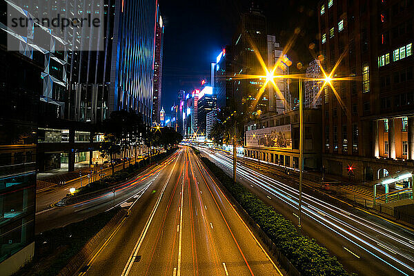 Außenansicht einer modernen Stadtlandschaft mit Langzeitbelichtung von Fahrzeugen auf der Straße in Hongkong