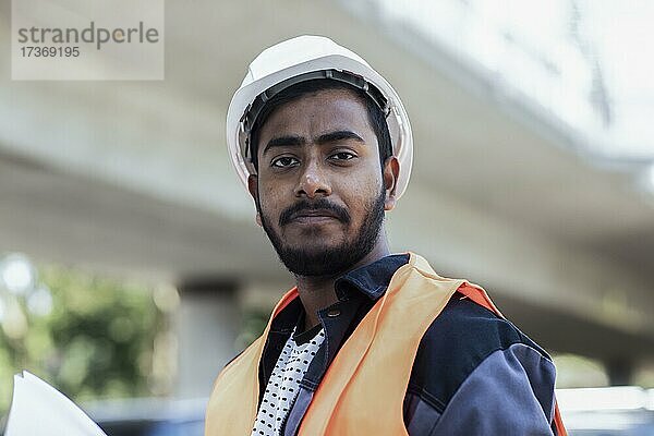 Junger Techniker mit Bart außen mit Helm arbeitend an einer Brücke  Baden-Württemberg  Deutschland  Europa