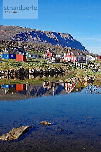Holzhäuser spiegeln sich im Wasser vor Gebirge  Qeqertarsuaq  Diskoinsel  Artkis  Grönland  Dänemark  Nordamerika