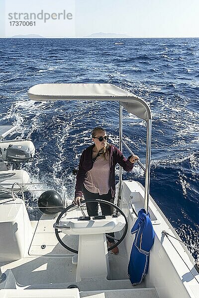 Junge Frau am Steuerrad im Cockpit an Deck eines Segel-Katamaran  Segeltörn  Dodekanes  Griechenland  Europa