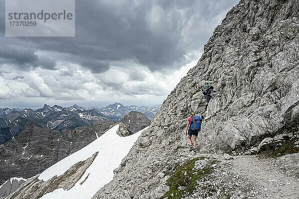 Zwei Wanderinnen  Bergsteigerin auf einem Weg mit Schneeresten  Bergpanorama  dramatischer Wolkenhimmel  Heilbronner Weg  Allgäuer Alpen  Allgäu  Bayern  Deutschland  Europa