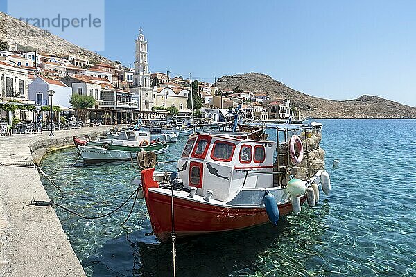 Fischerboote im Hafen von Chalki mit türkisblauem Wasser  Promenade mit bunten Häusern des Ortes Chalki  Chalki  Dodekanes  Griechenland  Europa