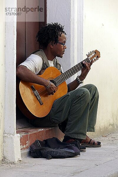 Junger  dunkelhäutiger Mann  Kubaner  mit Rastafrisur sitzt in Haustür und spielt Gitarre  Altstadt Hauptstadt Havanna  Provinz Havanna  Große Antillen  Karibik  Kuba  Mittelamerika