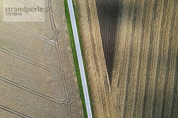Drohnenaufnahme  Straße durch abgeerntete Felder mit abstrakten Mustern  Agrarlandschaft bei Schildorn im Innviertel  Oberösterreich  Österreich  Europa