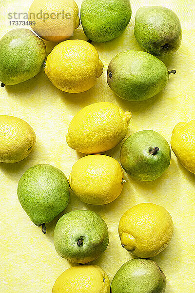 Blick von oben auf Zitronen und Birnen auf einer gelben Tischdecke