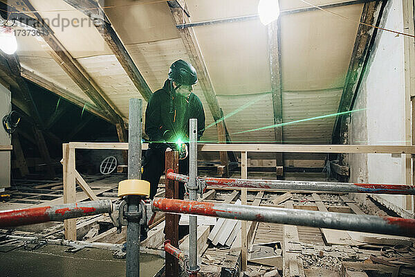Bauarbeiter  der den Laser in voller Länge benutzt  während er auf der Baustelle eine Wand misst