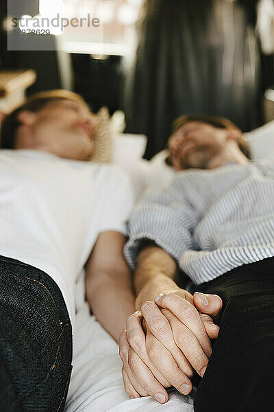 Homosexuelles Paar hält sich an den Händen  während es im Wohnmobil im Urlaub liegt