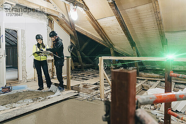 Männlicher Bauarbeiter im Gespräch mit einer Ingenieurin auf der Baustelle