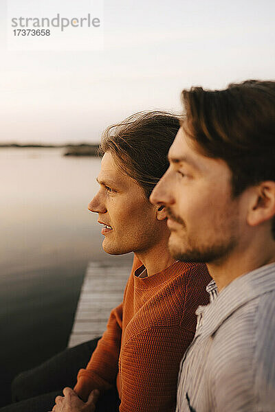 Homosexuelles Paar schaut weg  während es seine Freizeit am Seeufer verbringt