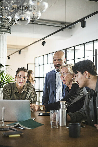 Beraterin diskutiert mit Hackern über Laptop im Kreativbüro