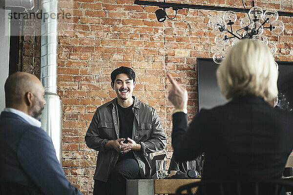 Lächelnder männlicher Unternehmer präsentiert seine Idee im Büro