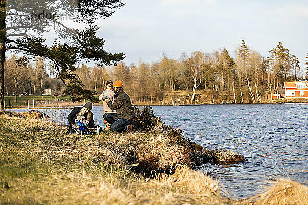 Mittlerer erwachsener Mann und Frau mit Kindern am See im Park
