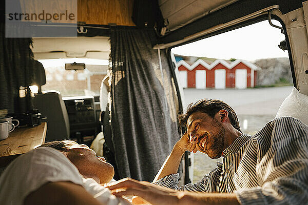Lächelnder Mann im Gespräch mit seinem Freund beim Ausruhen im Campingwagen