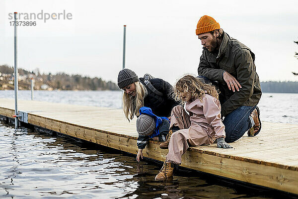 Mann und Frau mit Sohn und Tochter auf einem Steg am See