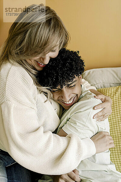 Glückliche Mutter und Sohn umarmen sich im Wohnzimmer