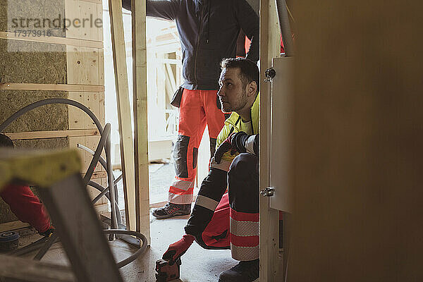 Männlicher Bauarbeiter  der auf einer Baustelle mit einem Laserwerkzeug arbeitet