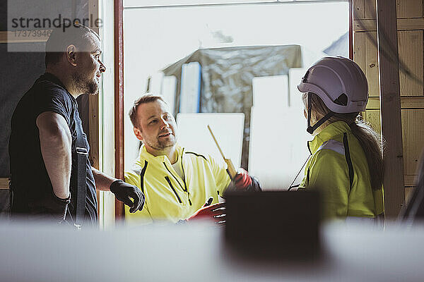 Männliche und weibliche Bauarbeiter diskutieren gemeinsam auf der Baustelle