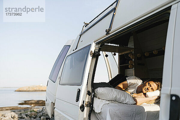 Mann entspannt sich im Campingwagen am Seeufer