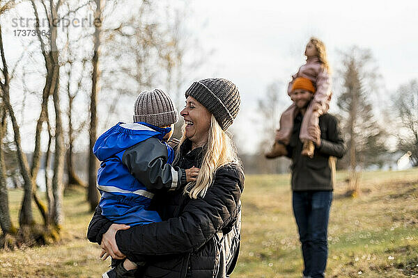 Fröhliche Mutter mit ihrem Sohn im Park stehend