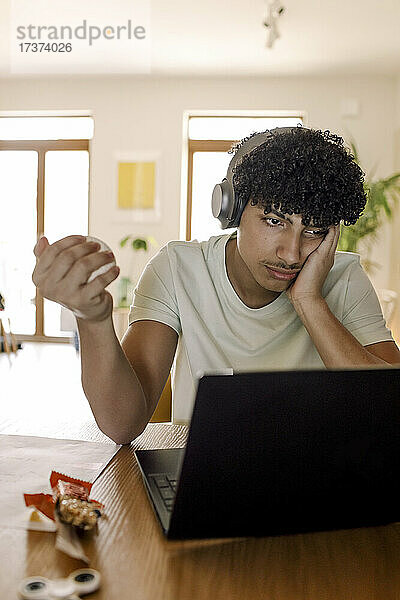 Männlicher Teenager  der einen Laptop benutzt  während er zu Hause sitzt