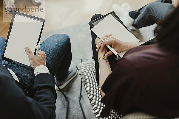 Hochformatige Ansicht einer Unternehmerin und eines Unternehmers mit digitalem Tablet im Unterricht
