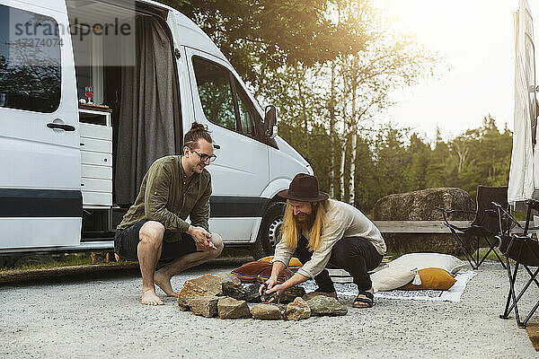 Männliche Freunde bereiten ein Lagerfeuer am Wohnmobil vor