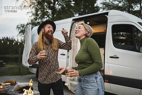Glückliches junges Paar tanzt abends am Campingwagen