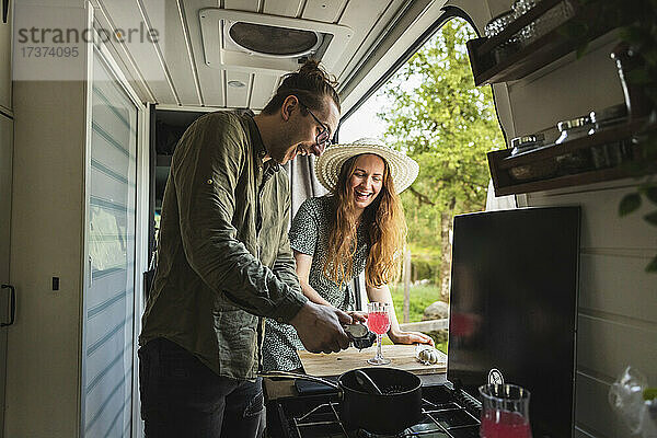 Glückliches Paar bei der Zubereitung von Saft in einem Campingwagen im Urlaub