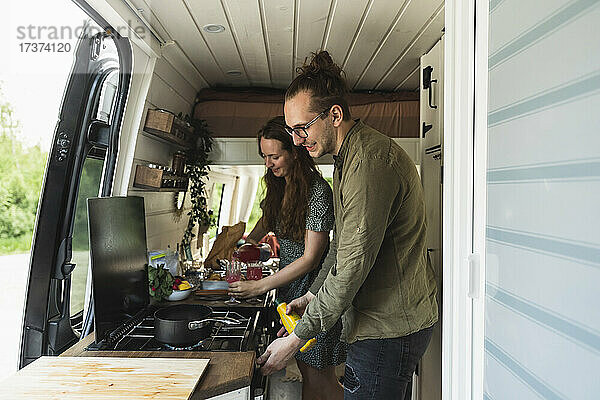 Heterosexuelles Paar bei der Essenszubereitung im Campingwagen im Urlaub