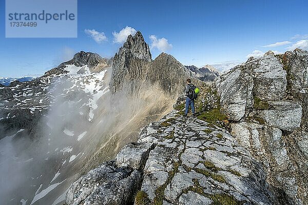 Wanderer am Gipfel der Westlichen Törlspitze  hinten fesliger Grat und Gipfel der Partenkirchner Dreitorspitze  Wettersteingebirge  Garmisch Partenkirchen  Bayern  Deutschland  Europa