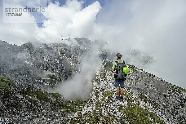 Wanderer auf Wanderweg zur Meilerhütte  hinten wolkenverhangene felsige Berggipfel Oberreintalschrofen und Großer Hundtsallkopfe  Frauenalpl  Wettersteingebirge  Bayern  Deutschland  Europa