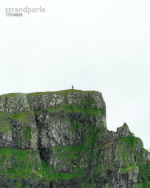 Eine Person steht in der Entfernung auf einer Klippe  Sandvik  Suduroy  Faroer Inseln