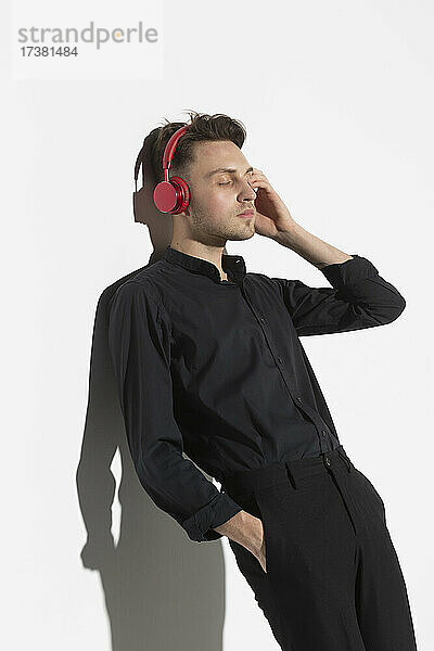 Gelassener junger Mann mit Kopfhörern beim Musikhören