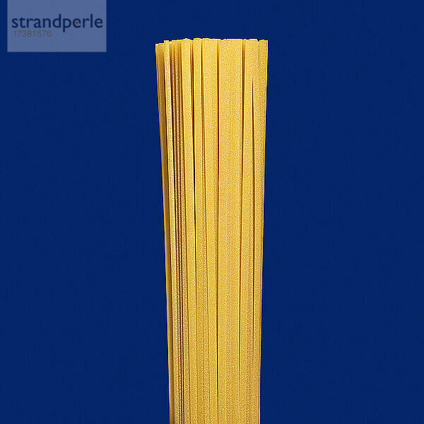 Close up ungekochte Spaghetti Nudeln auf blauem Hintergrund