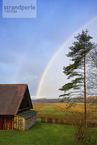 Ländliche Szene  ein Regenbogen am Himmel über einer Scheune  nach Regen.