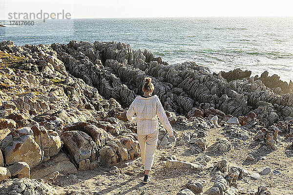 Teenager-Mädchen am Strand  Erkundung der zerklüfteten Felsen bei Sonnenuntergang