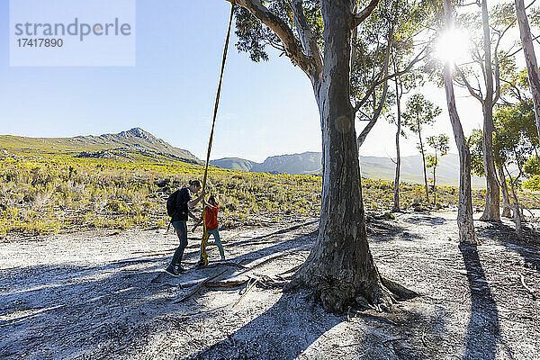 Teenager-Mädchen und jüngerer Bruder benutzen eine Seilschaukel auf einem Wanderweg