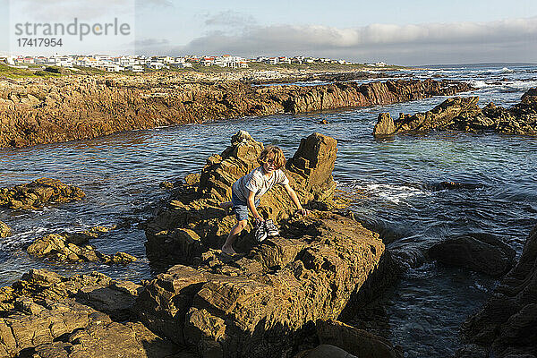 Ein kleiner Junge erkundet die Felspools an der zerklüfteten Felsküste des Atlantiks