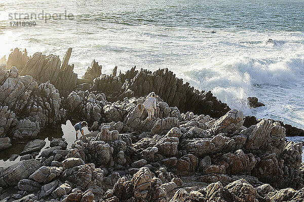 Zwei Kinder erkunden zerklüftete Felsen und Felsbecken am Meer