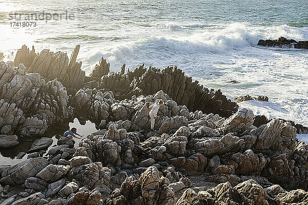 Zwei Kinder erkunden zerklüftete Felsen und Felsbecken am Meer