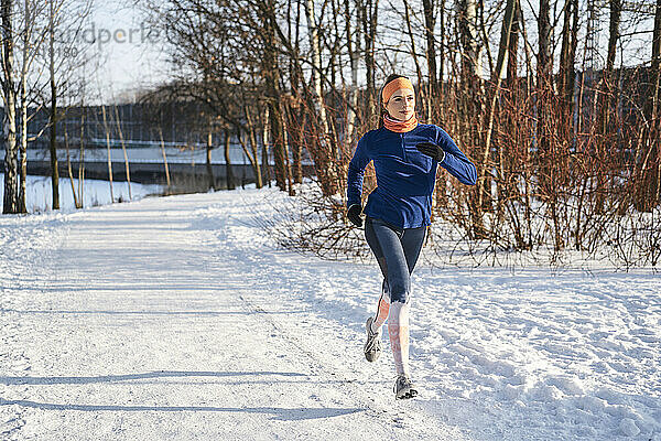 Frau läuft an sonnigem Tag auf Schnee