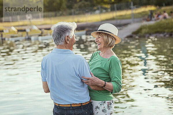 Fröhliches älteres Paar schaut einander an  während es am See steht