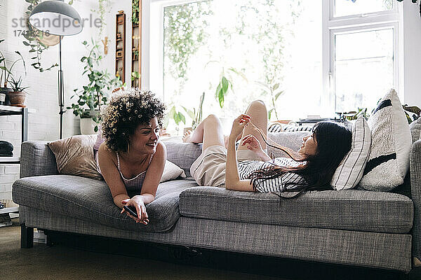 Freundinnen reden  während sie sich zu Hause auf dem Sofa ausruhen