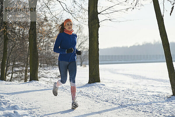 Junge Frau joggt im Winter auf Schnee