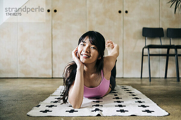 Lächelnde Frau trainiert  während sie auf einer Decke liegt