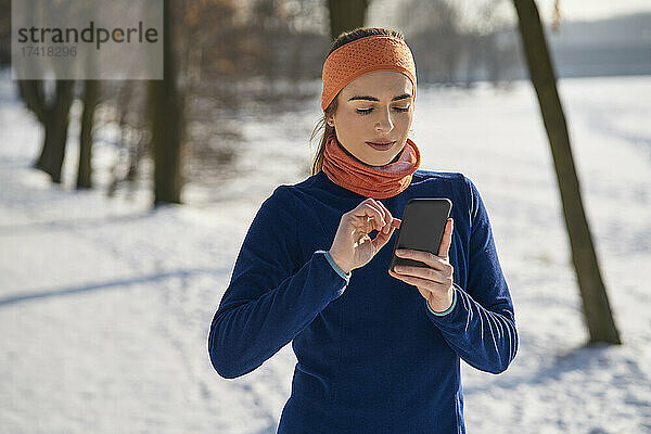 Frau benutzt Smartphone im Winter