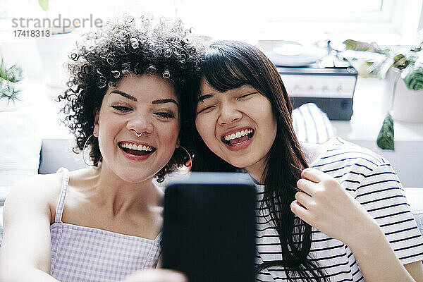 Fröhliche Freundinnen machen zu Hause ein Selfie mit dem Smartphone