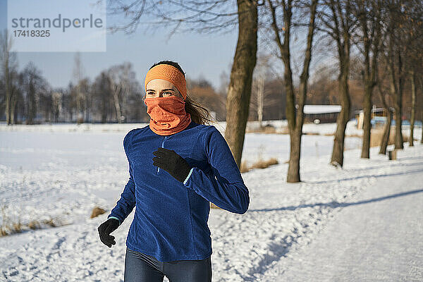 Frau trägt Gamaschen-Gesichtsmaske beim Laufen im Winter